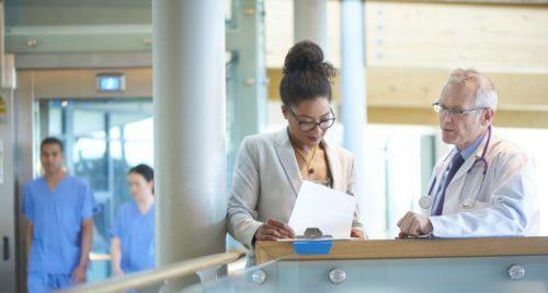 Pharmacist consulting with nearby doctor at hospital